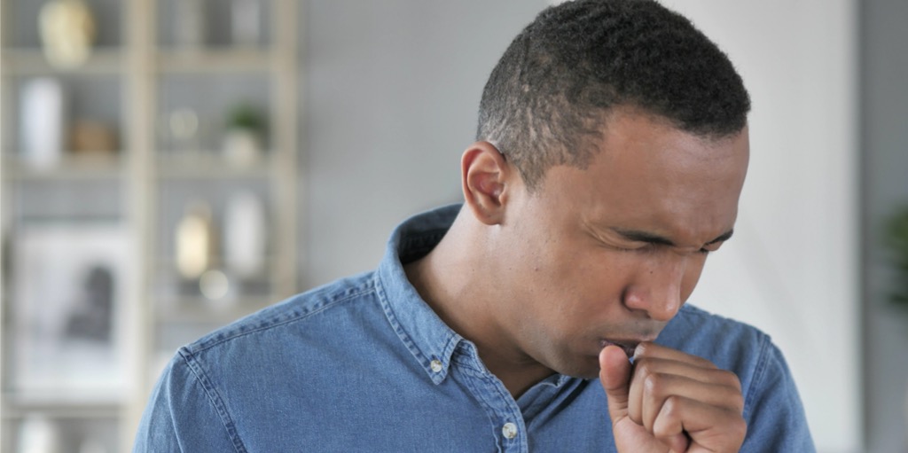 cough-portrait-of-sick-young-african-man-coughing-at-work-picture-id1039474056