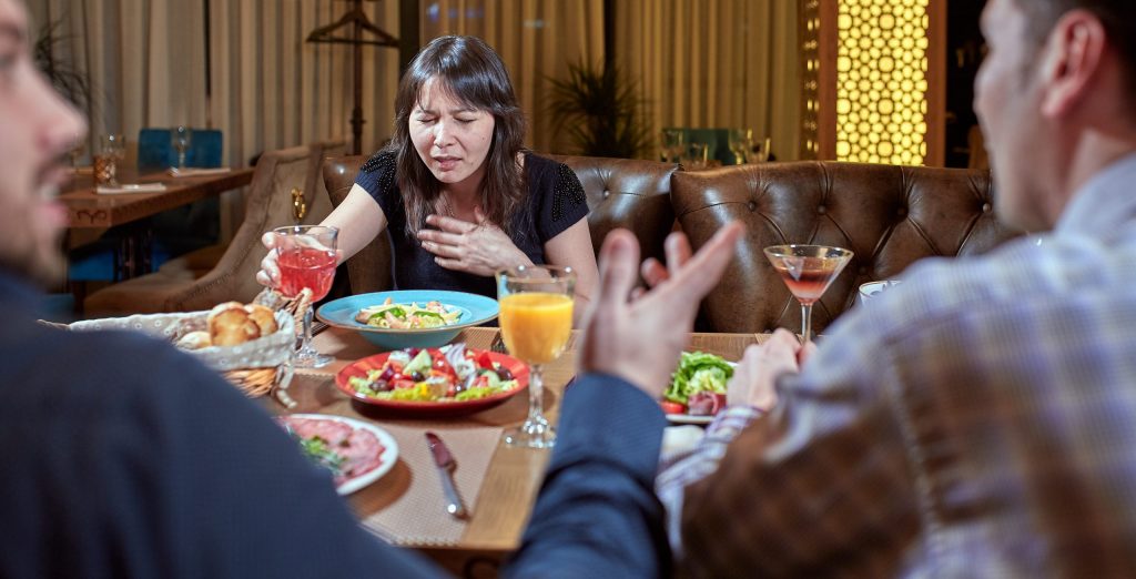 Woman Feeling Sick While Eating Bad Food in a Restaurant. Dinner customer having a bad experience feeling sick.