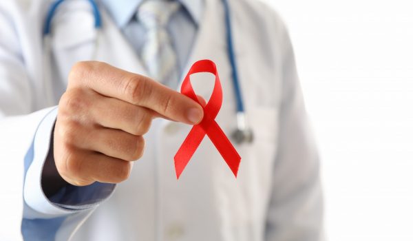 Doctor holds a red ribbon, close up and space for text